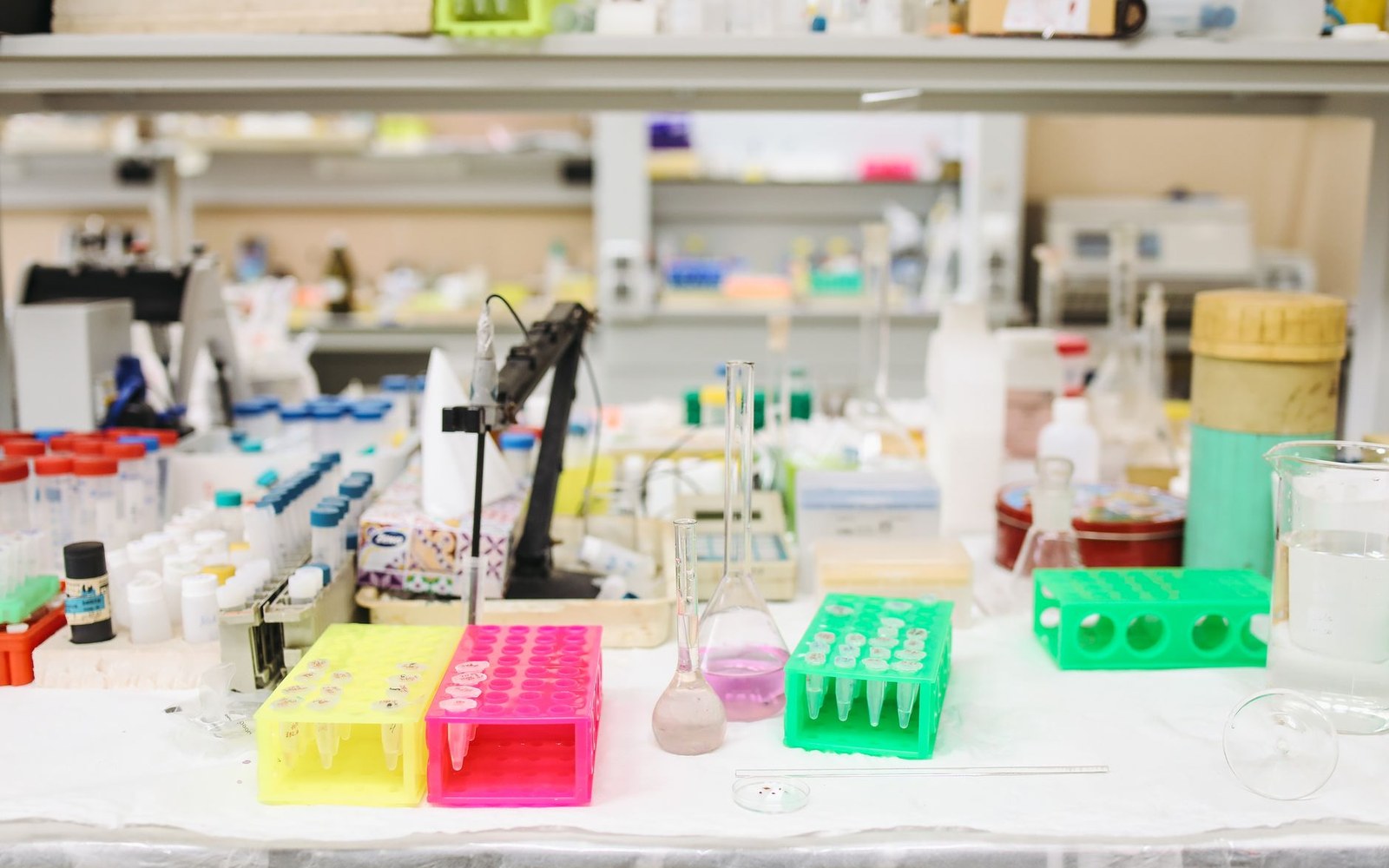Colorful test tube racks and flasks cluttered on a laboratory bench