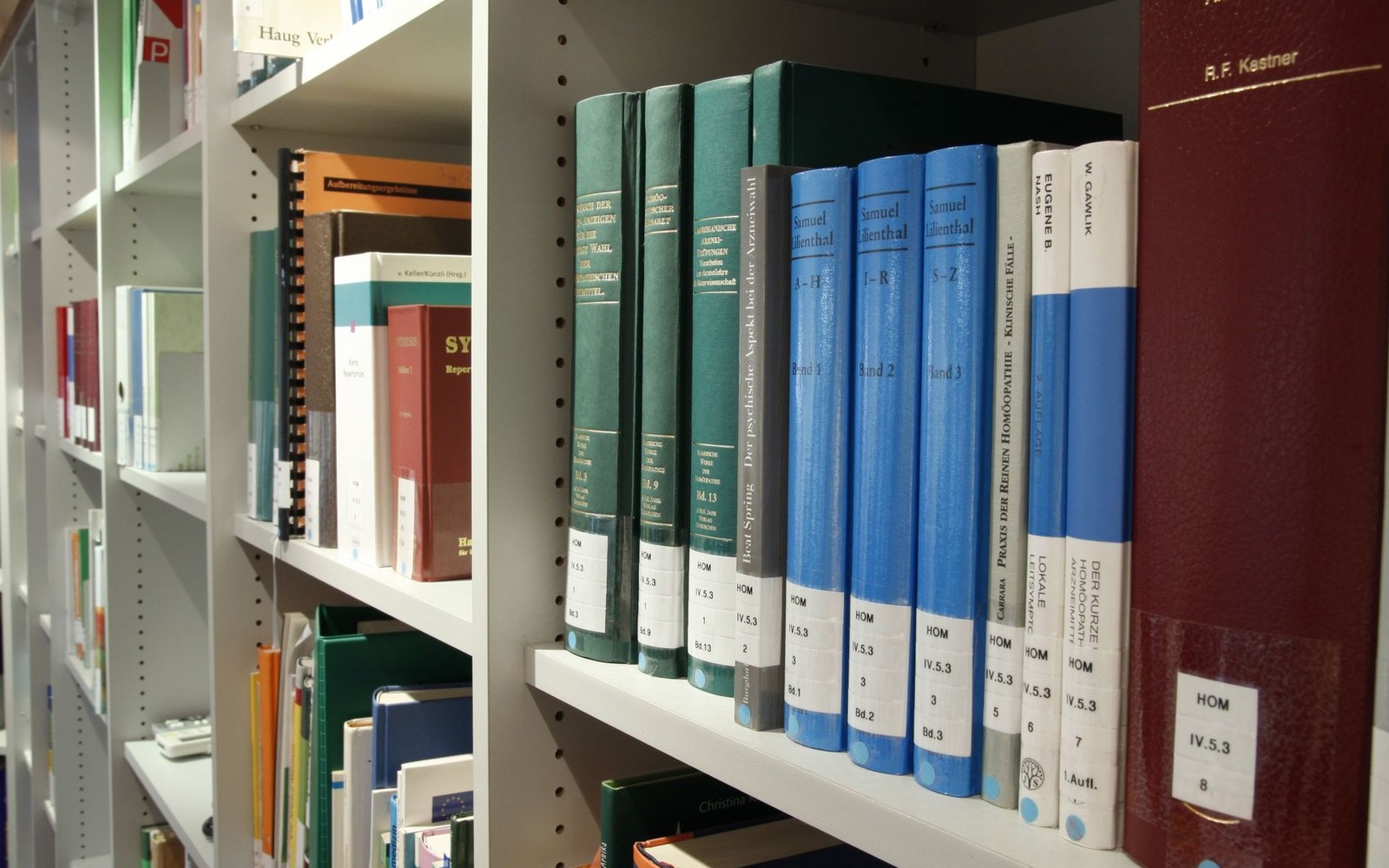 Rows of German homeopathic reference books lined up on library shelves
