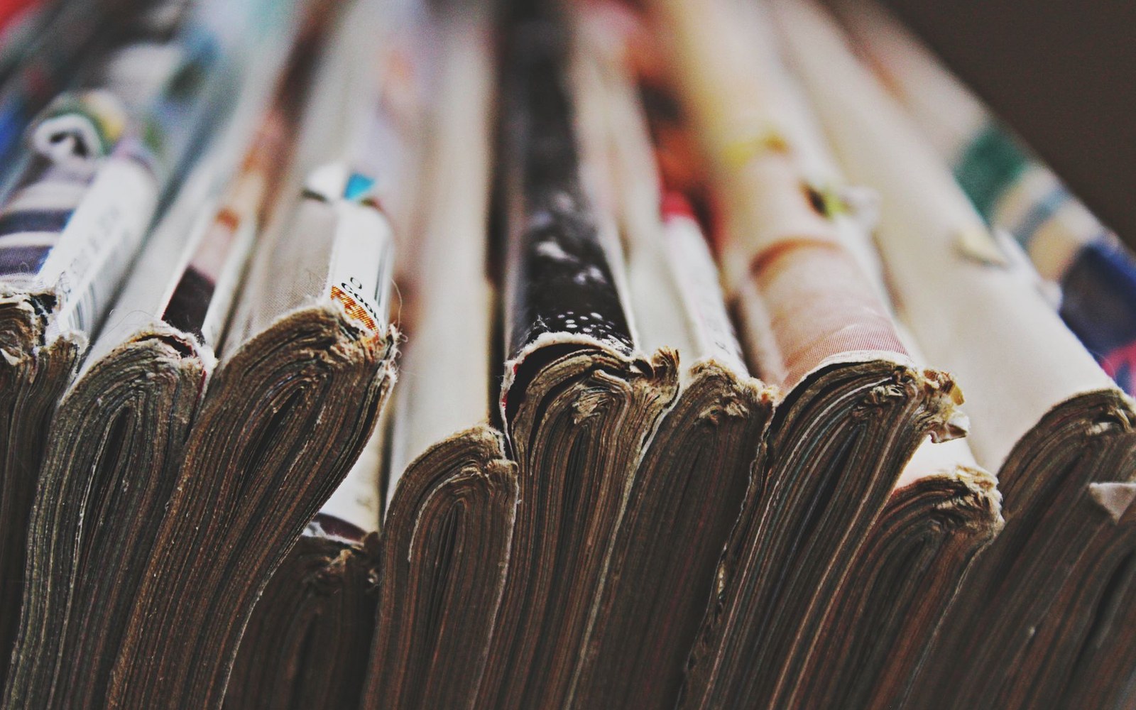 Close-up of stacked folded newspapers showing worn spines and edges