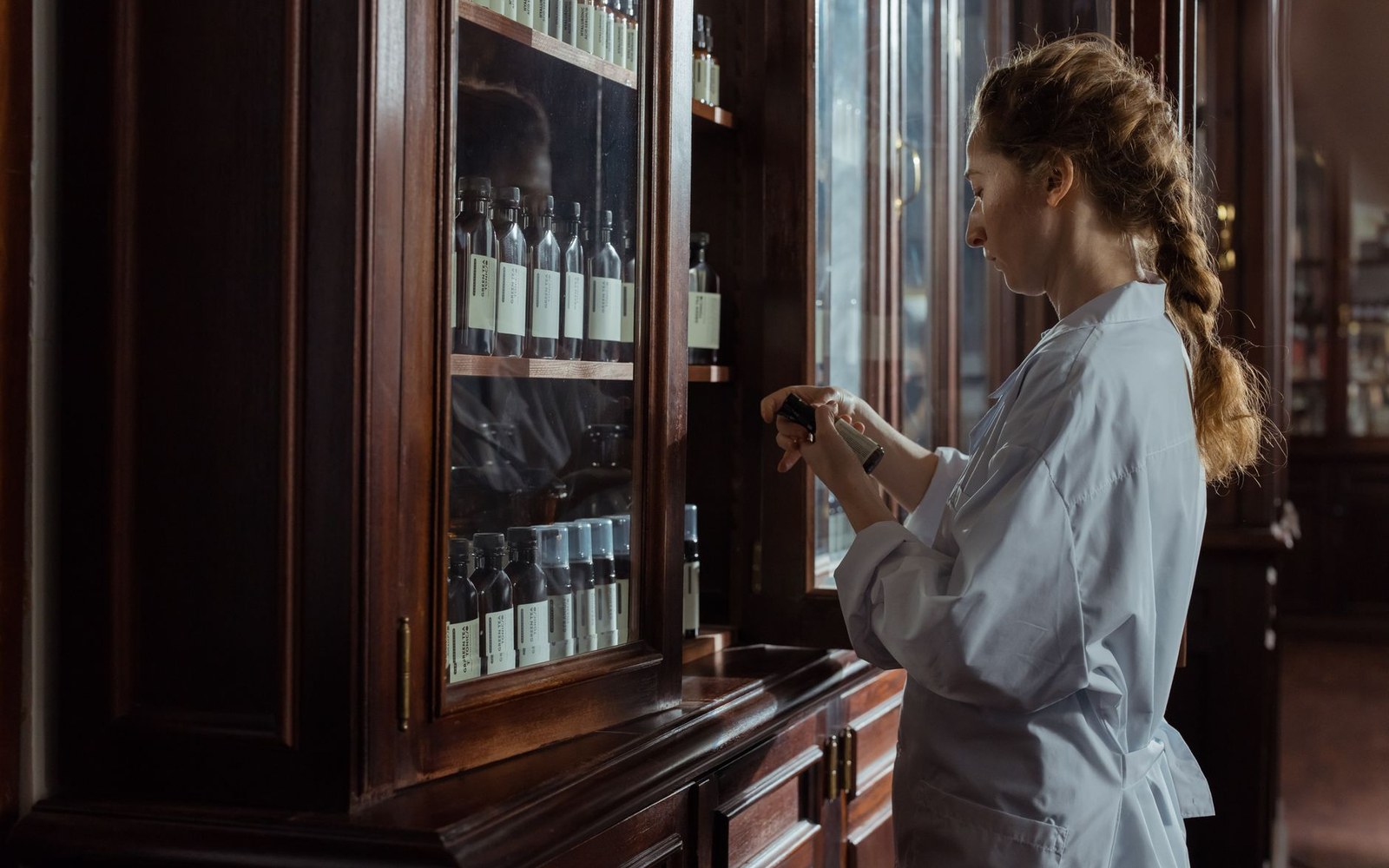 A wooden apothecary case of labelled homeopathic vials, arranged in rows, shot from directly above